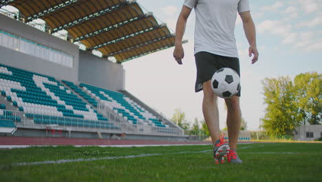 Professional-Male-soccer-player-athlete-on-the-football-field-in-slow-motion-in-sports-equipment-juggles-a-soccer-ball.-A-football-player-with-a-ball-in-the-stadium-near-the-stands